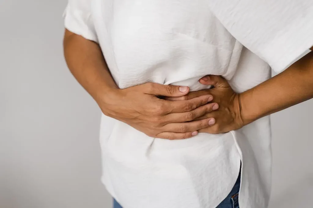 a woman suffering from PCS or pelvic congestion syndrome, touching her mid-section